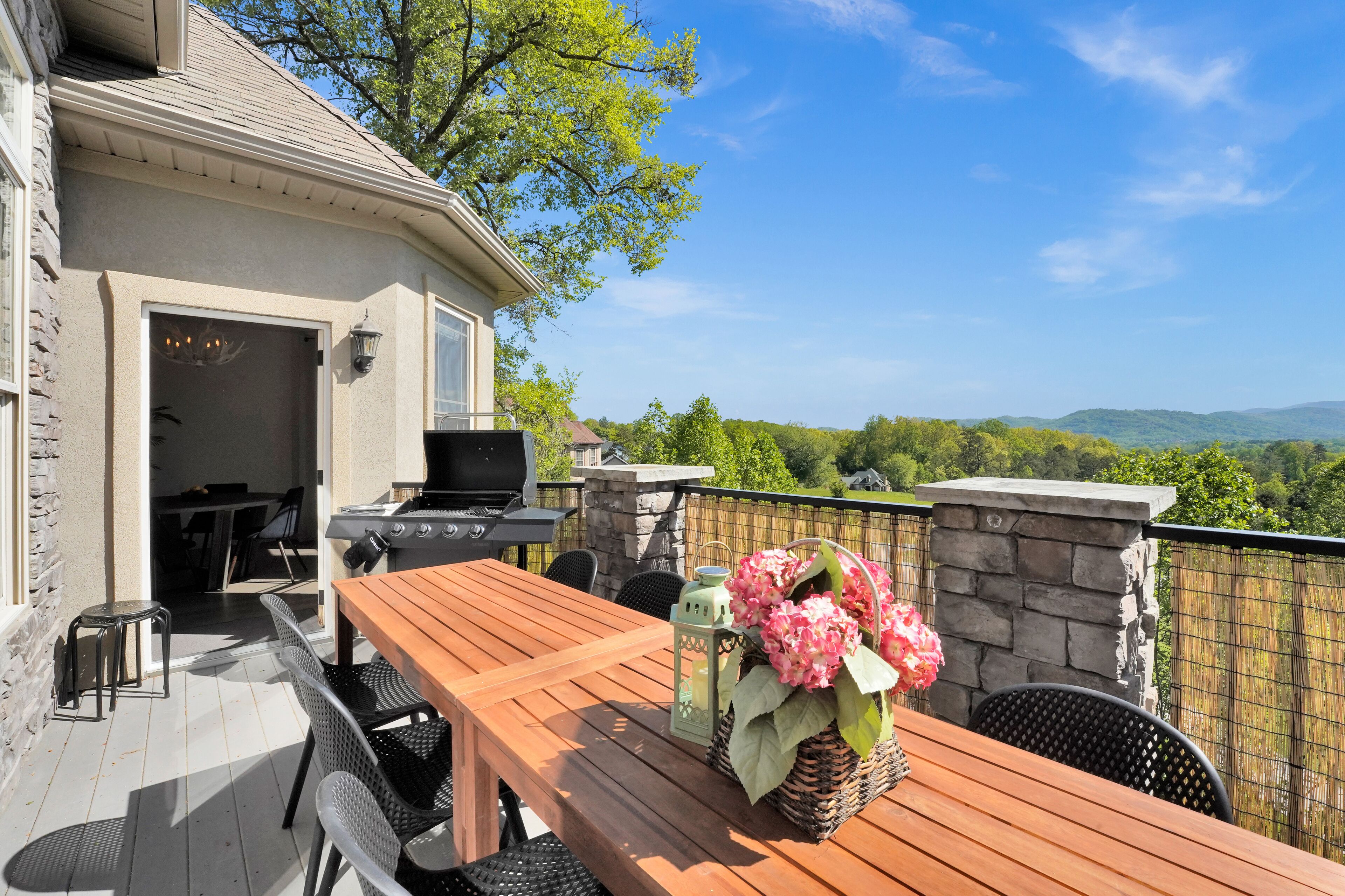 Eine Terrasse im Freien mit einem Holztisch, Stühlen und einem Grill.