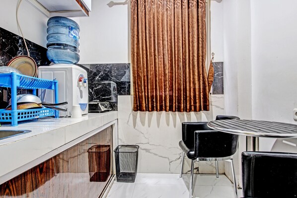 Una cocina compacta con dispensador de agua, un escurreplatos azul y salpicadero de mármol.