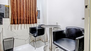 A small, modern room with a marble wall, a round table, two black chairs, and a brown curtain. - Collection O 90253 DHelomi (Depok)