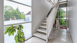A staircase with white railings leading to a landing. A potted plant is visible on the left side. - Collection O 90253 DHelomi (Depok)