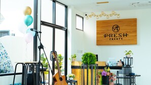 A modern reception area with a wooden sign reading "FRESH resort," a guitar, and various potted plants. - Fresh Resort Pattaya (Pattaya)