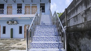 A staircase with blue and white patterned tiles leading to a building with a balcony. - OYO Life 90433 Serasi Kost (Palembang)