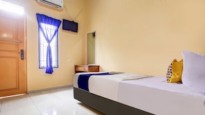 A hotel room with a bed, a window with blue curtains, a bedside table, a mirror, and a wall-mounted TV. - OYO Life 90433 Serasi Kost (Palembang)
