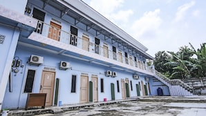 A multi-story building with numbered doors, air conditioning units, and a staircase leading to the upper floor. - OYO Life 90433 Serasi Kost (Palembang)