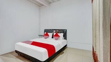 A neatly made bed with a white and red bedspread, a black headboard, and two decorative pillows.