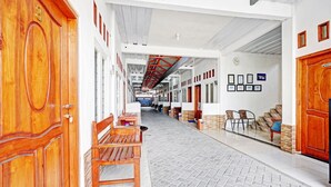 Passadís amb portes de fusta, seients i un paviment de rajoles.