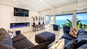 A modern living room with a fireplace, large windows, and a view of the ocean. - Oceanfront, Hot Tub, Private Beach, Fire Pit (Oceanside)