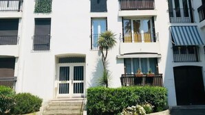A multi-story residential building with balconies, a central entrance, and a small garden area. - F3 Lumineux Tout Équipé sur la Route des Plages (Perpignan)