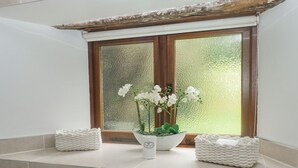 A bathroom with a window, a white sink, and two white baskets on the ledge. - Cowslip Barn (Totnes)
