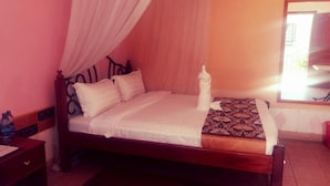 A bed with a canopy, a bedside table, and a patterned rug. - Hotel Bison (Nakuru)