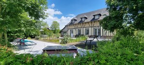 Een traditioneel vakwerkhuis met een binnentuin, een kleine vijver en terrasplekken.