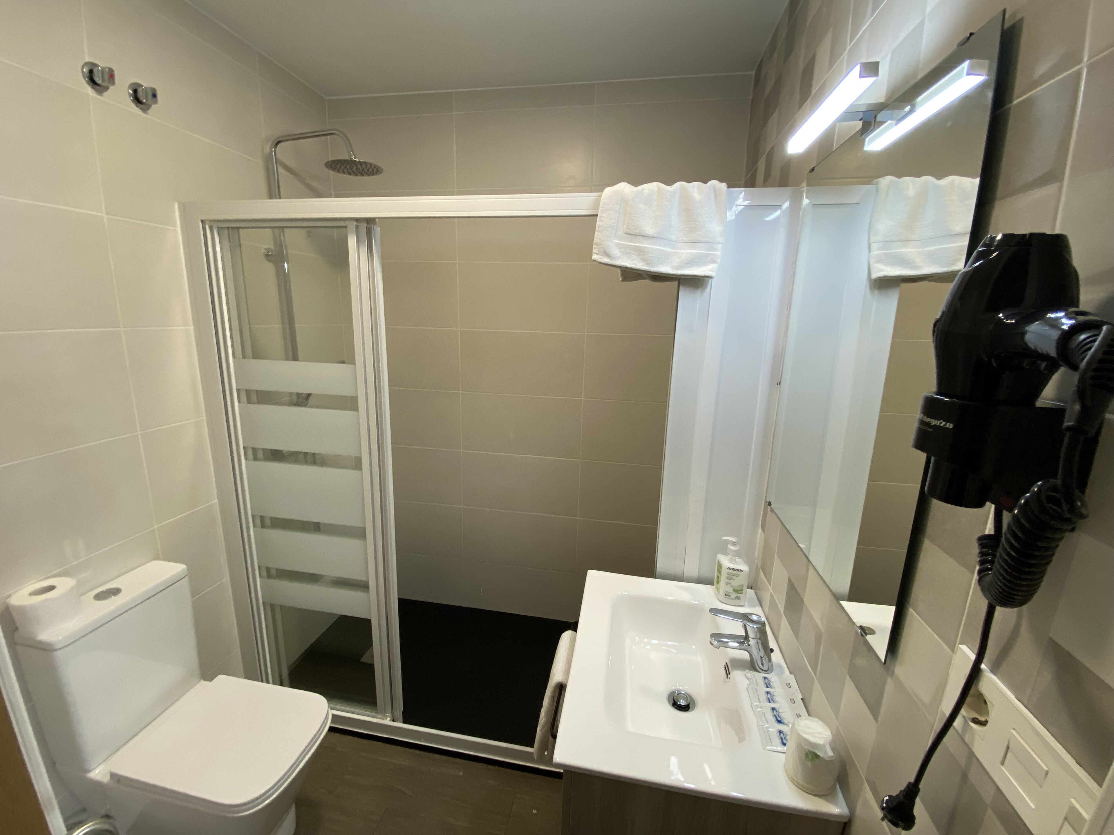 A bathroom with a toilet, sink, and shower.