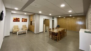 Una amplia sala de reuniones con una gran mesa y sillas, un armario de madera y dos sofás.