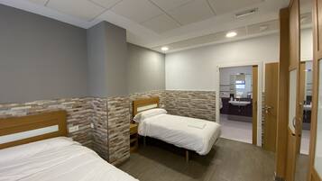A hotel room with two single beds, a wooden headboard, a small bedside table, and a bathroom visible through an open door.