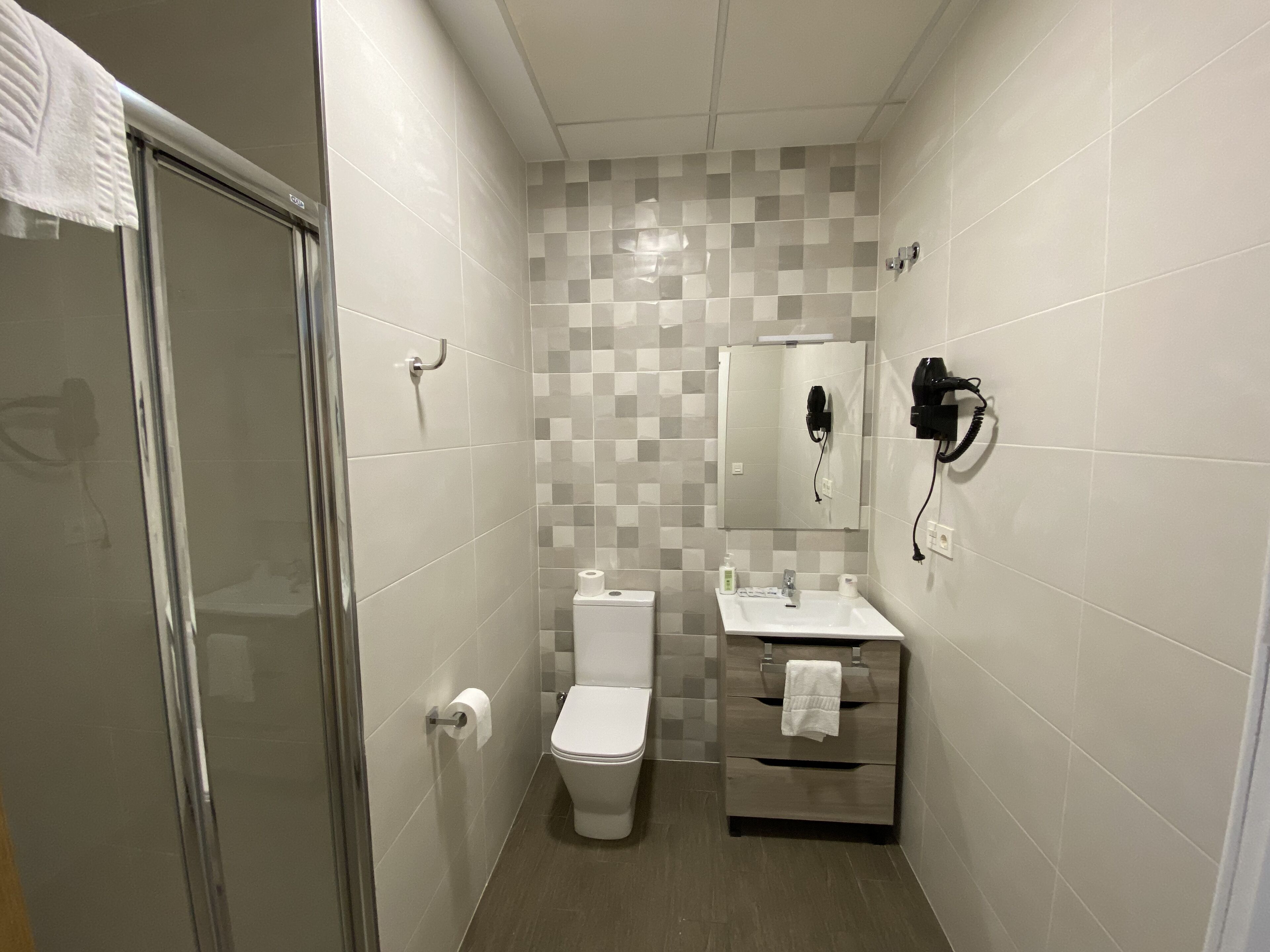 A small bathroom with a toilet, sink, and a mirror.