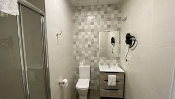 A small bathroom with a toilet, sink, and a mirror.