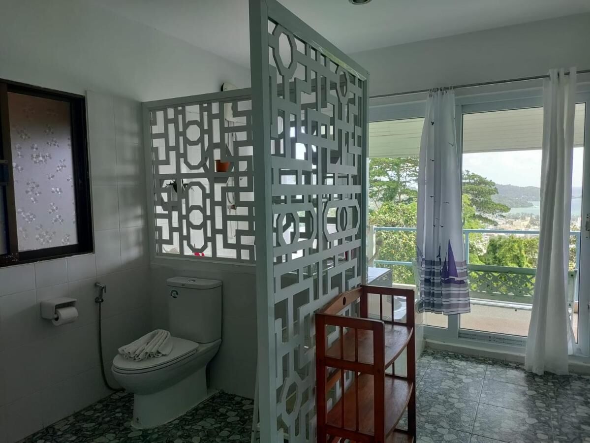 Un baño con inodoro, ducha y balcón con vistas.