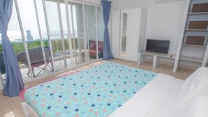 Une chambre avec un lit, une télévision, une armoire et un balcon avec vue.