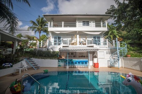 Una piscina al aire libre, sombrillas, sillones reclinables de piscina