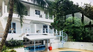 Un espace piscine doté d’un bar, de coins salon et d’un escalier menant à un balcon.