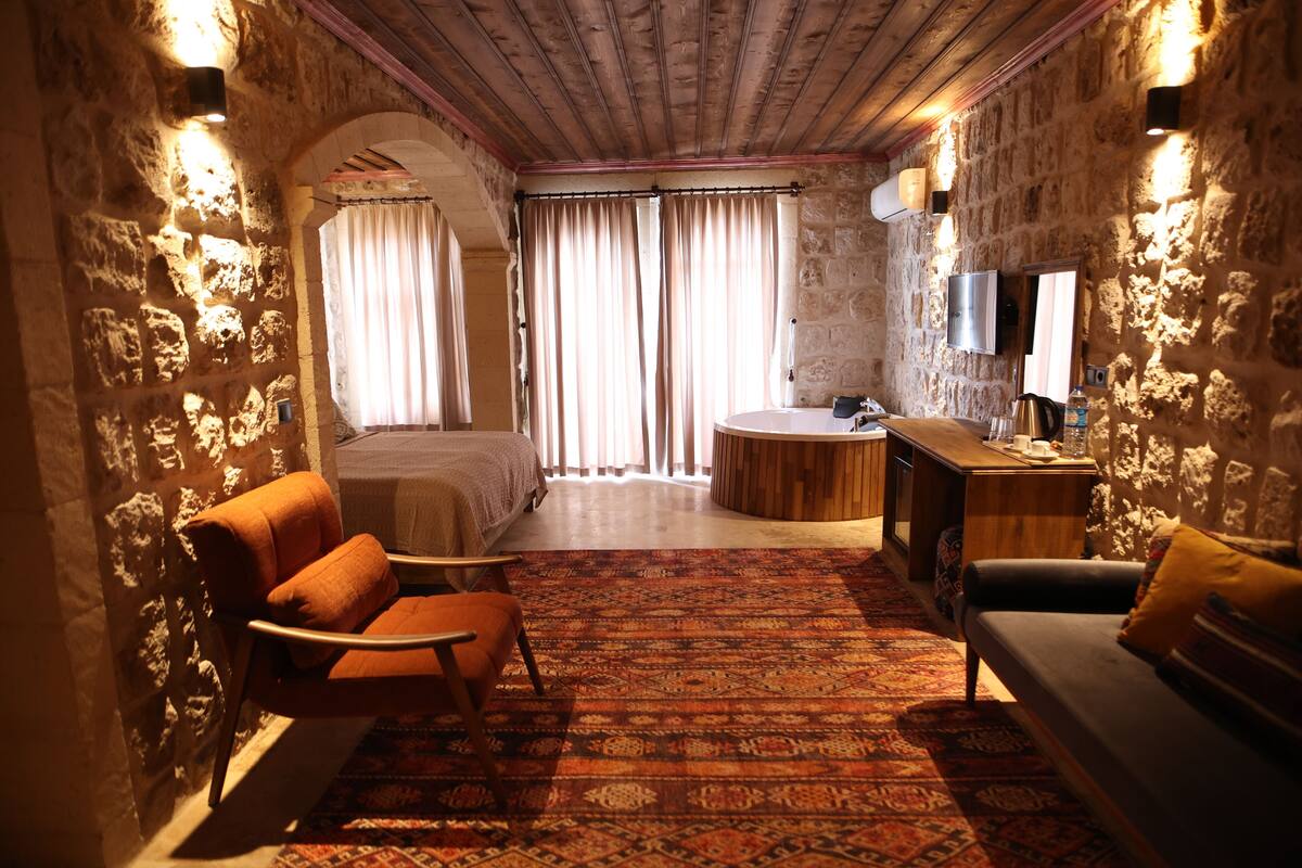 Una habitación con cama, sofá, mesita y televisor.