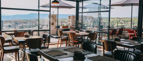 Un restaurante con ventanas amplias, mesas y sillas de madera.