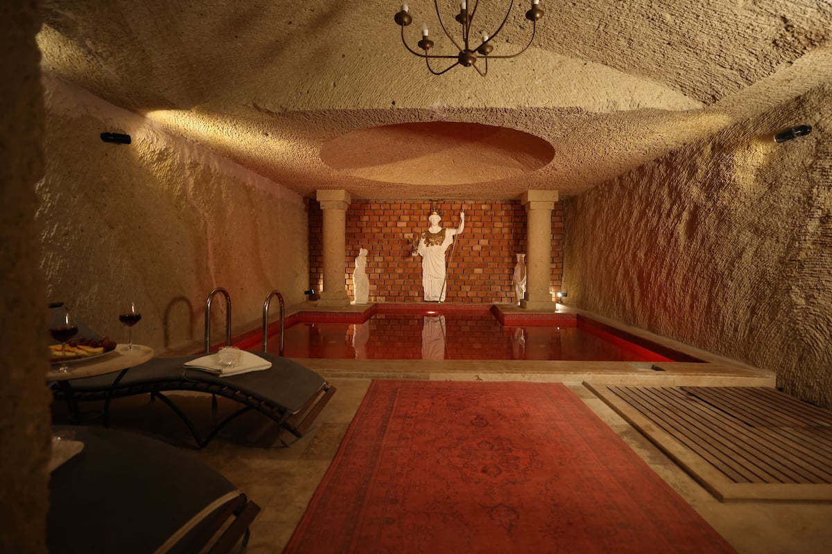 Una habitación con alfombra roja, un candelabro, pared de ladrillo y una estatua.