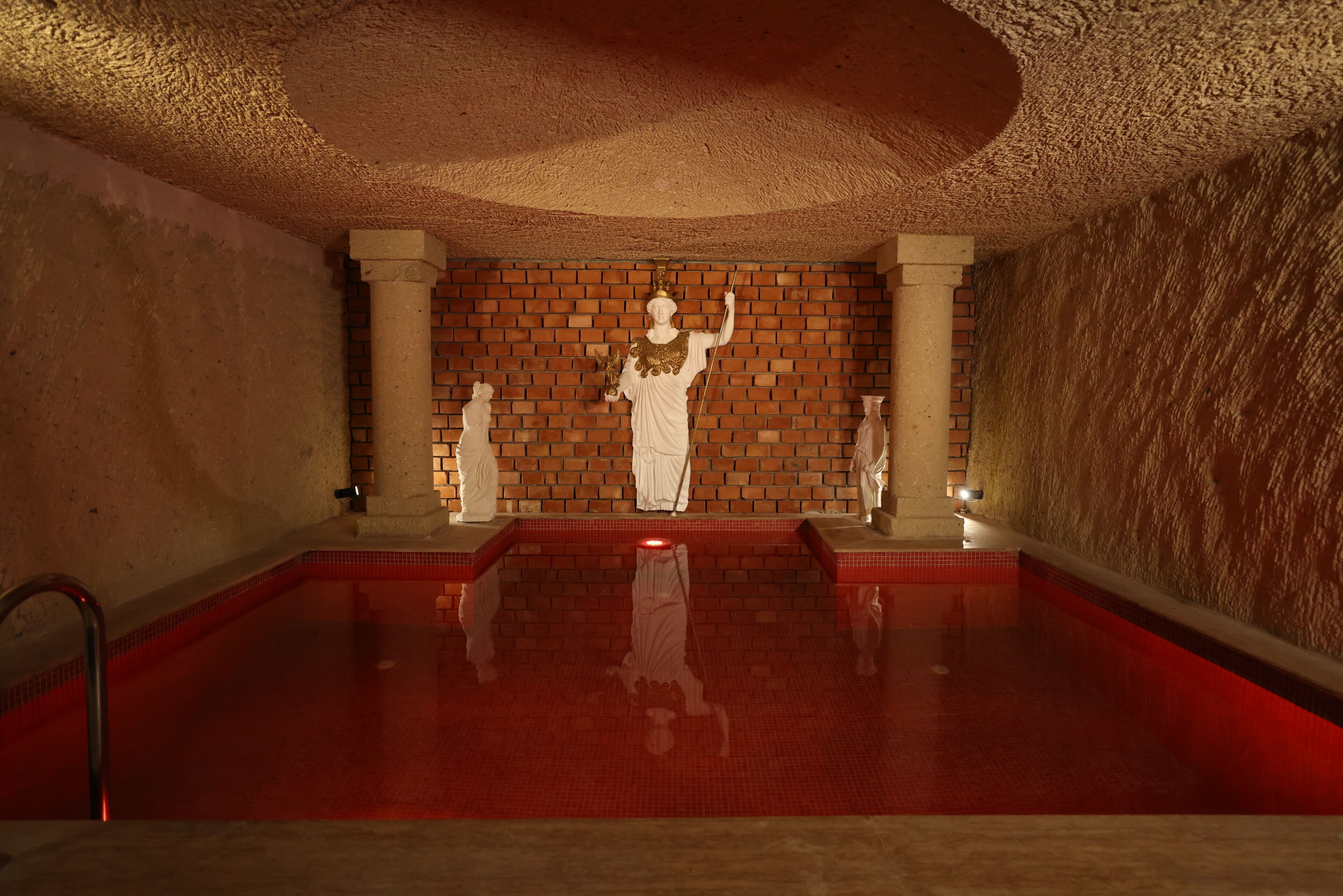 Una piscina amb estàtues, un mur de maó i un sostre amb relleu.