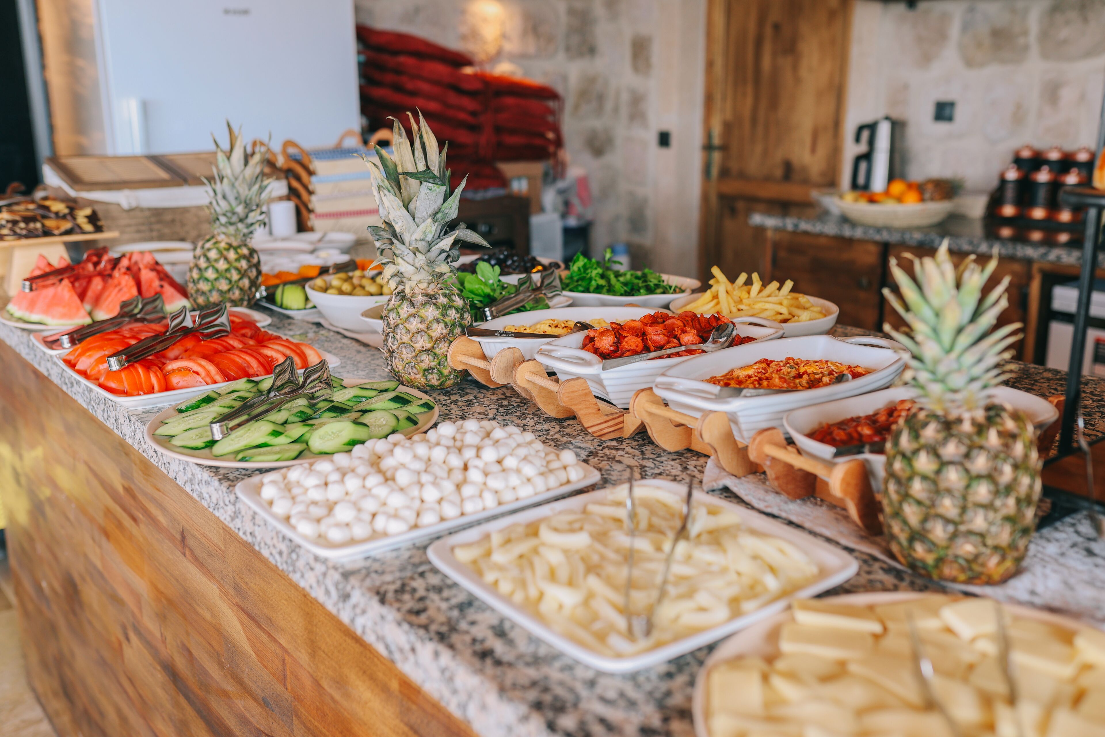 A buffet with various food items including fruits, vegetables, and cheeses.