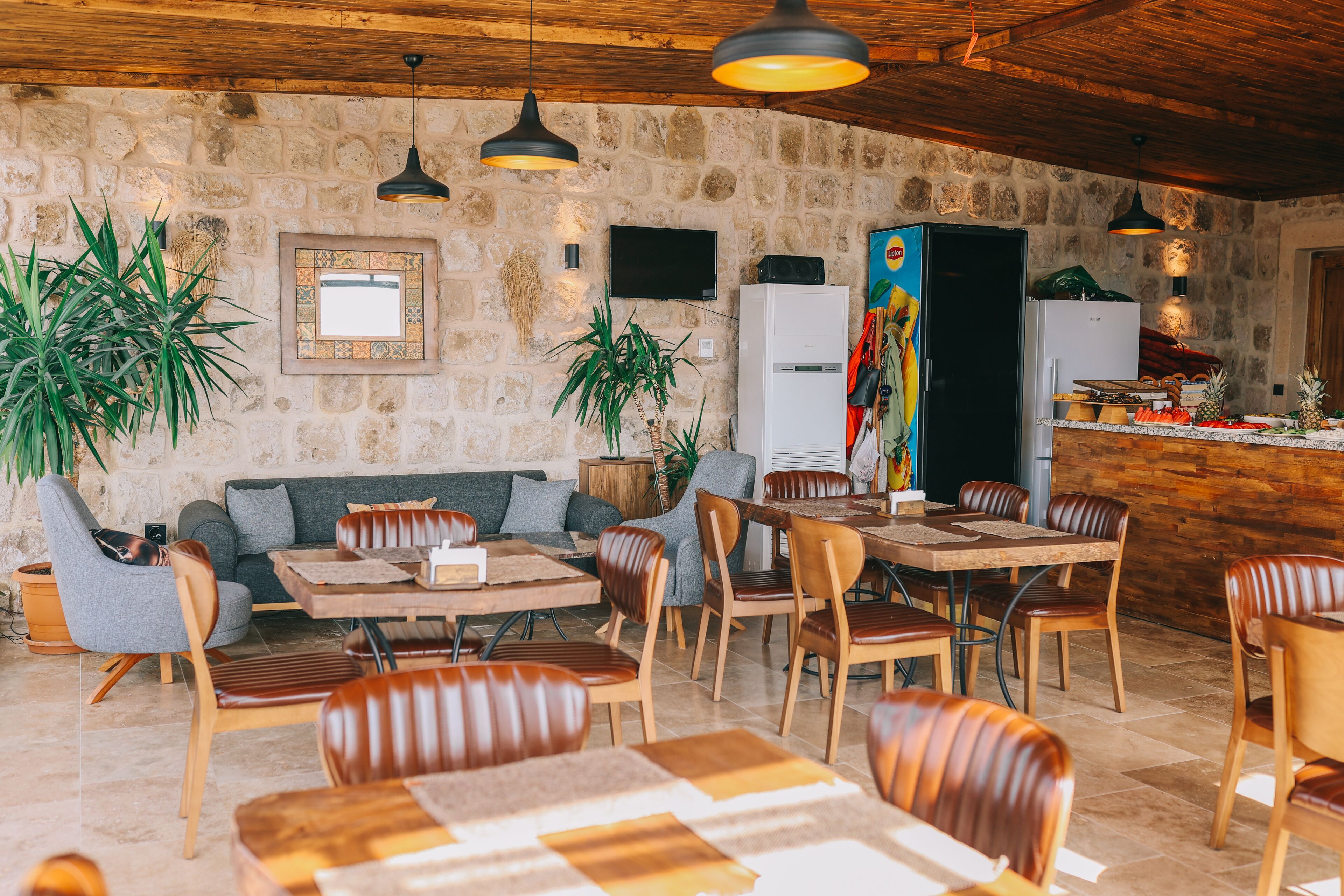 Un intérieur rustique avec des murs en pierre, des meubles en bois et des lampes suspendues.