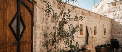 A rustic stone building with a wooden door and potted plants.