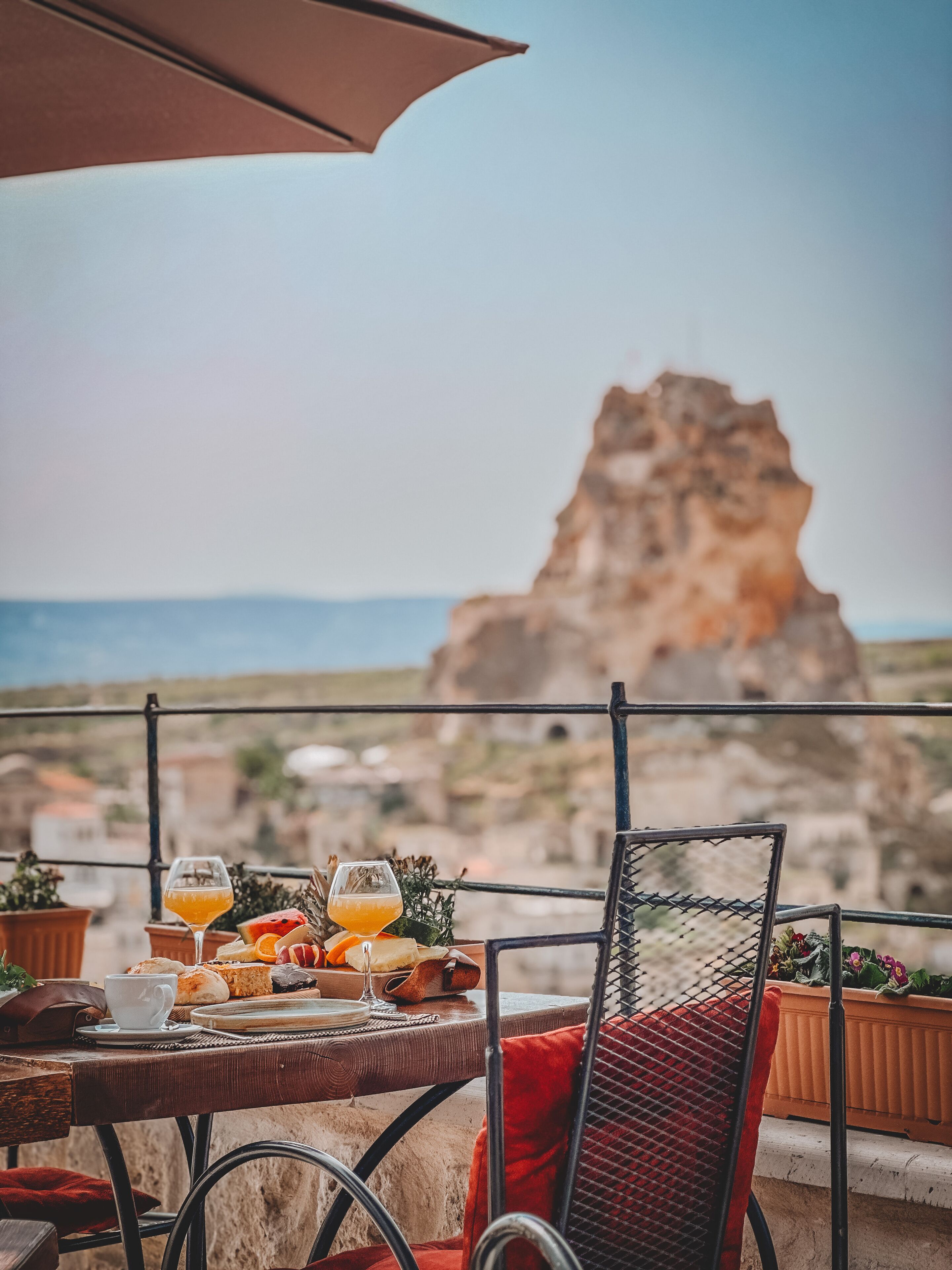 Una mesa con bebidas y pasteles, con vista a un paisaje rocoso y el mar.