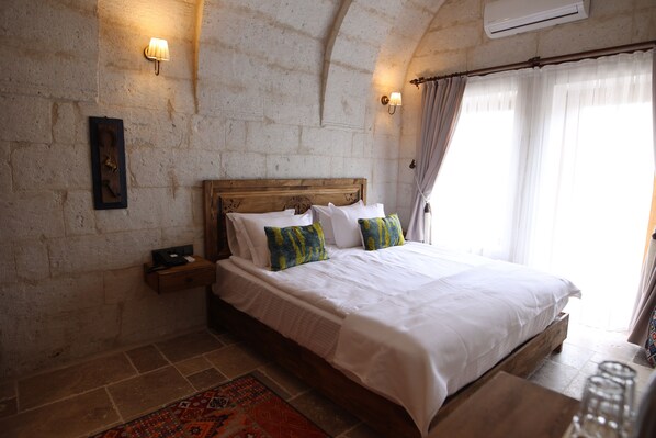 A bedroom with a wooden bed, a nightstand, a wall-mounted lamp, and a patterned rug.