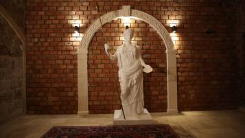 Una estatua en una habitación con paredes de ladrillo y una alfombra estampada.