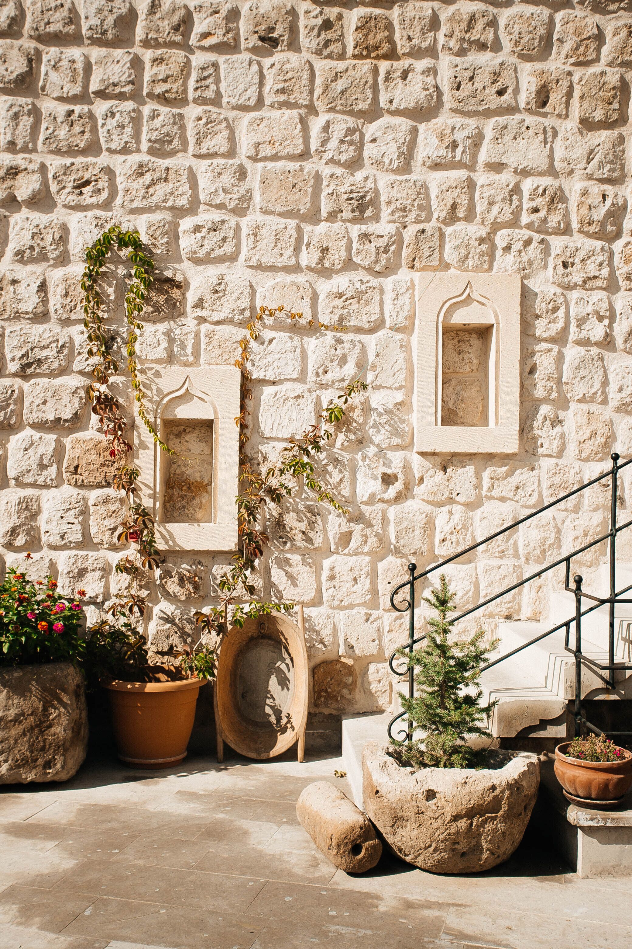 A stone wall with two rectangular frames and potted plants.