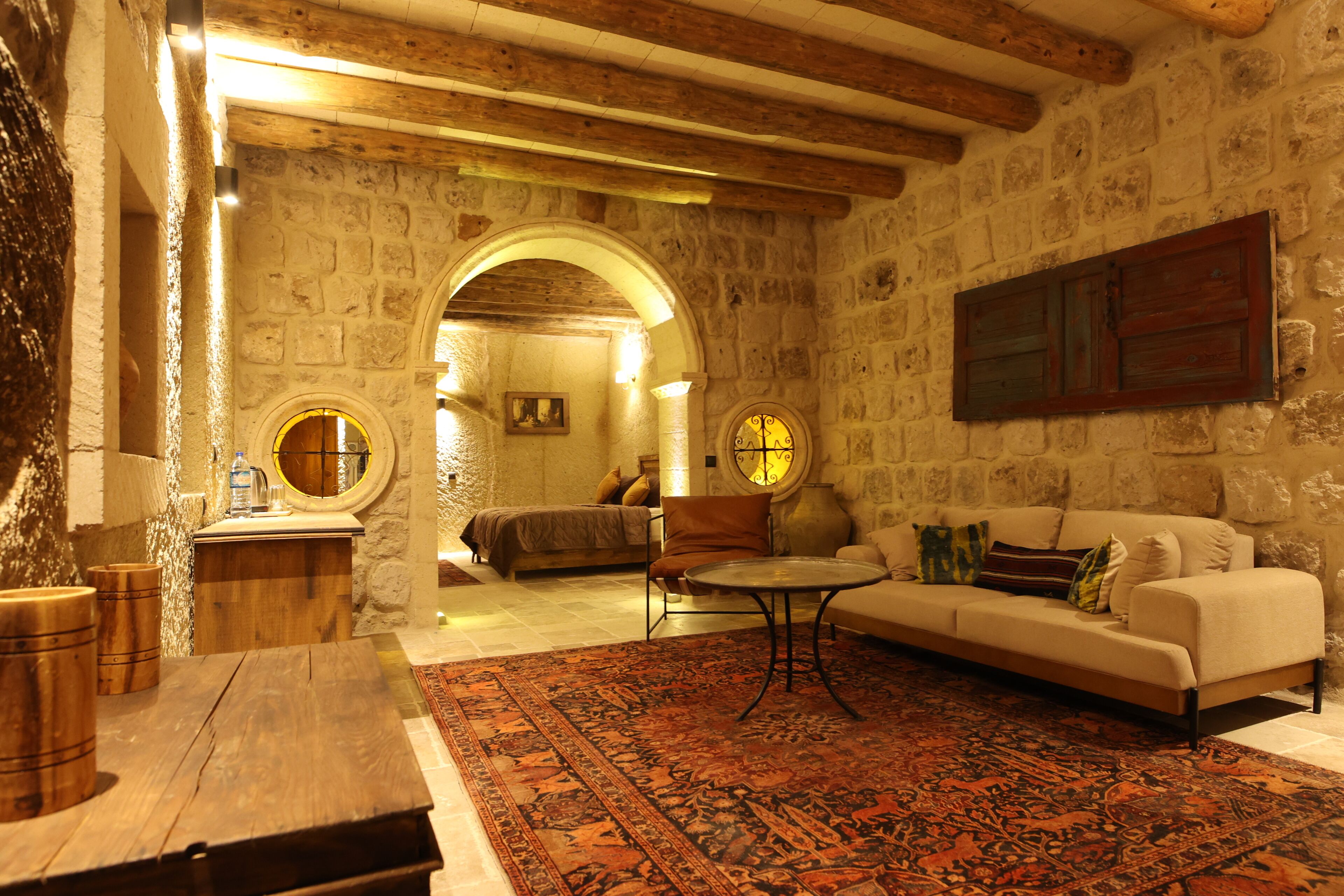 Une pièce aux murs de pierre, avec une table en bois, un canapé et un tapis à motifs.