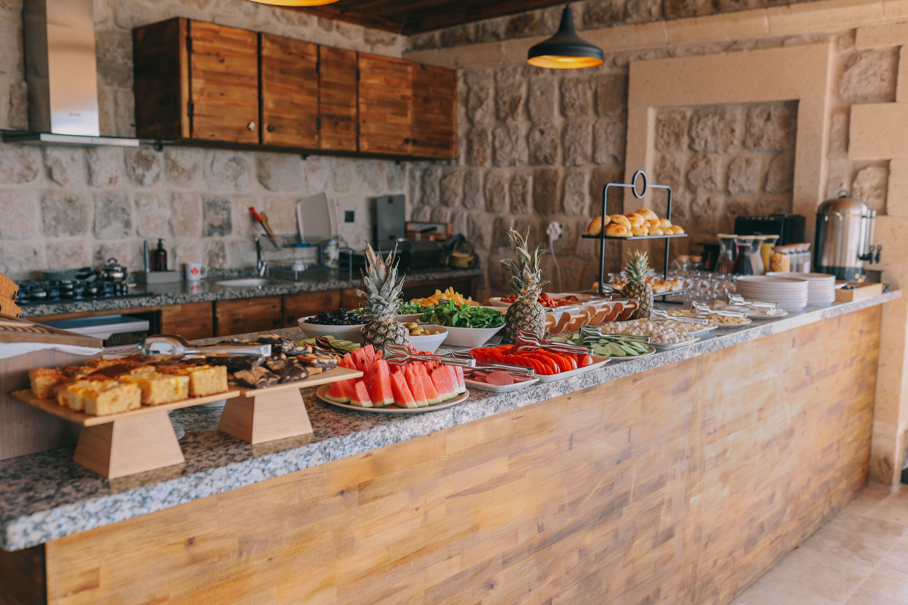 Een buffet met diverse soorten eten, zoals watermeloen, ananas en brood.