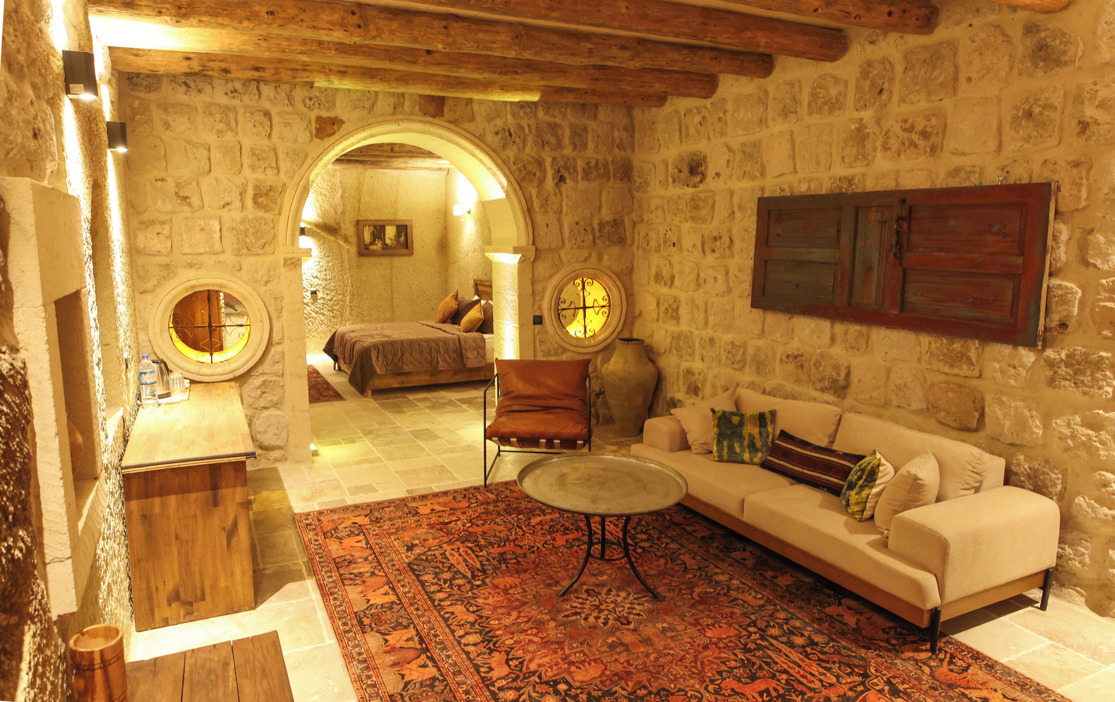 A stone-walled room with a bed, a sofa, a coffee table, and a chair.