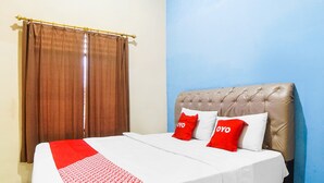 A hotel room with a bed, two red and white pillows, a red and white patterned blanket, and a window with brown curtains. - Hotel O Sky Residence Cengkeh (Medan)