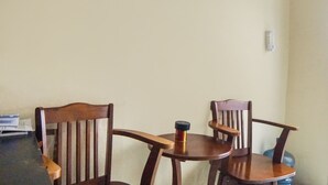 A small dining area with two wooden chairs and a round table, a water dispenser, and a power outlet on the wall. - Hotel O Sky Residence Cengkeh (Medan)