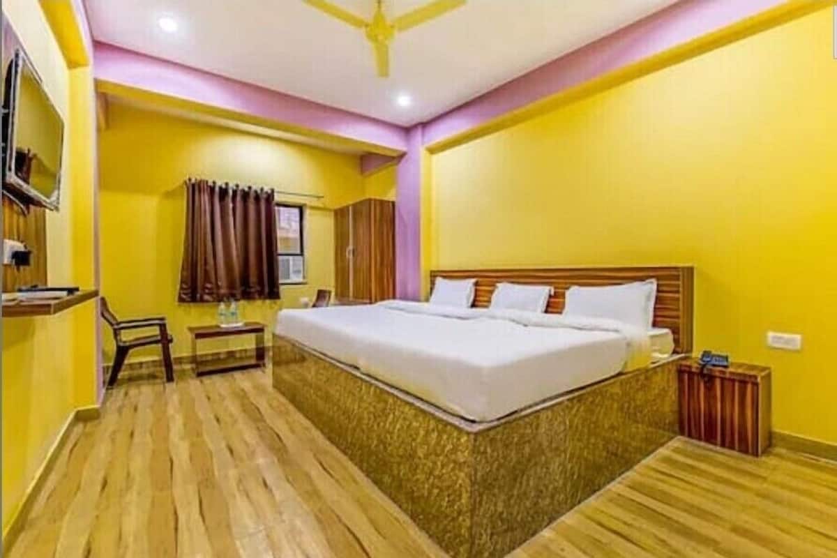 A hotel room with a large bed, a desk, a chair, and a wardrobe.