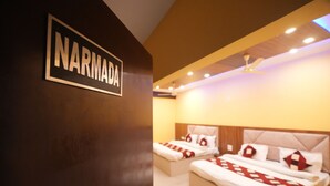 A hotel room with two beds, a ceiling fan, and a sign that reads "NARMADA". - SJH Venkatesh (Haridwar)