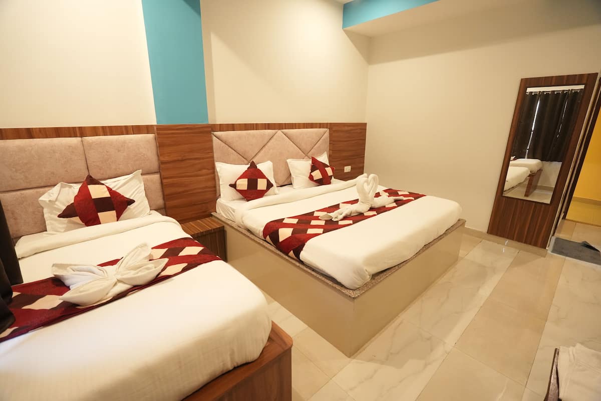 A hotel room with two beds, each with a wooden headboard, white bedding, and red and white checkered throw pillows. There is a mirror on the wall and a wooden nightstand between the beds.
