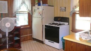 Eine kleine Küche mit Kühlschrank, Herd und Abluftventilator.