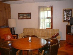 Relax in this inviting living room with a dining table, comfortable sofa, and mounted TV.