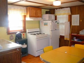 Compact kitchen with a gas stove, refrigerator, and microwave, perfect for preparing meals.