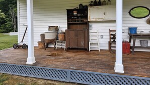 A porch with a wooden bench, a small table, and various antique items like jars and a lantern. - Early1880s farmhouse in rural Eastern Kentucky Appalachia. (Booneville)