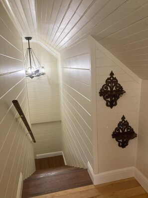 Una escalera estrecha con escalones de madera y paredes blancas.