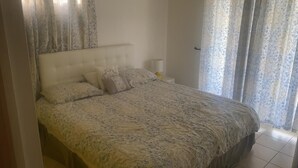 A bedroom with a bed, curtains, and a nightstand. - Spacious apartment with pool and gorgeous views of Marigot! (Marigot)