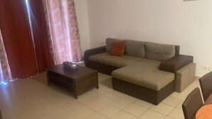 A living room with a sectional sofa, a small wooden coffee table, and a chair. - Spacious apartment with pool and gorgeous views of Marigot! (Marigot)